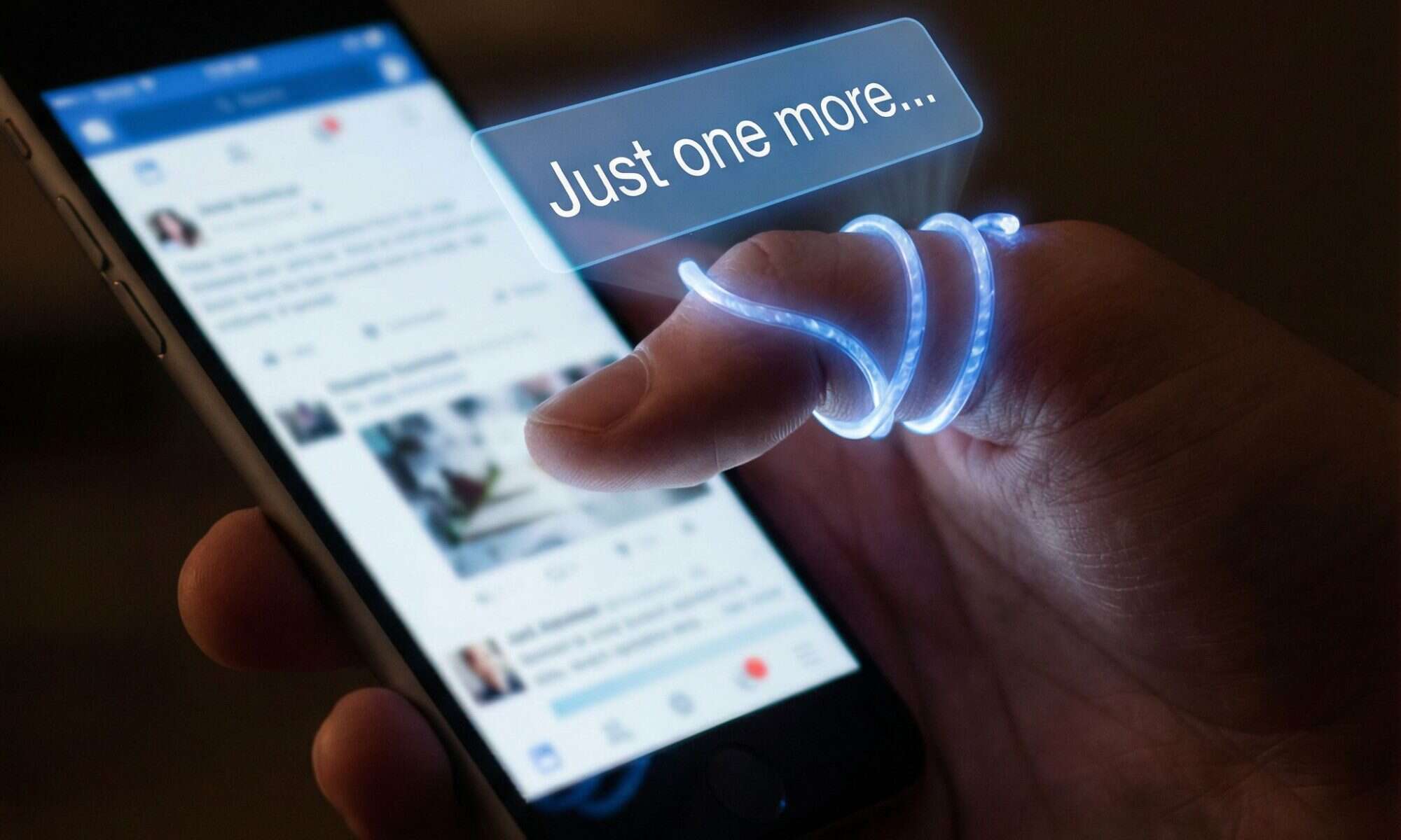 손가락을 휘감은 빛나는 알림 배너가 "한 번만 더..."라고 표시되며 휴대폰을 쥔 손을 조종하는 모습이다.