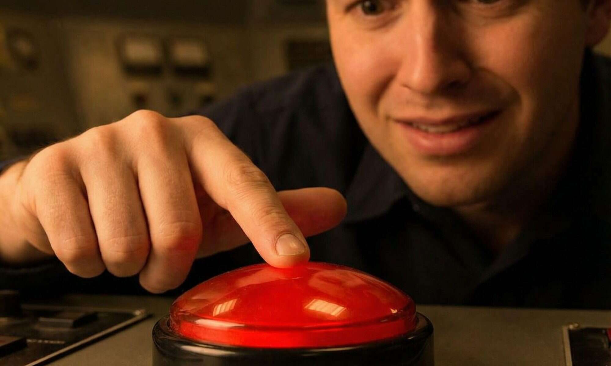 한 사람이 빛나는 커다란 빨간 버튼 위에 손가락을 올린 채 호기심과 갈등이 섞인 표정을 짓고 있습니다.